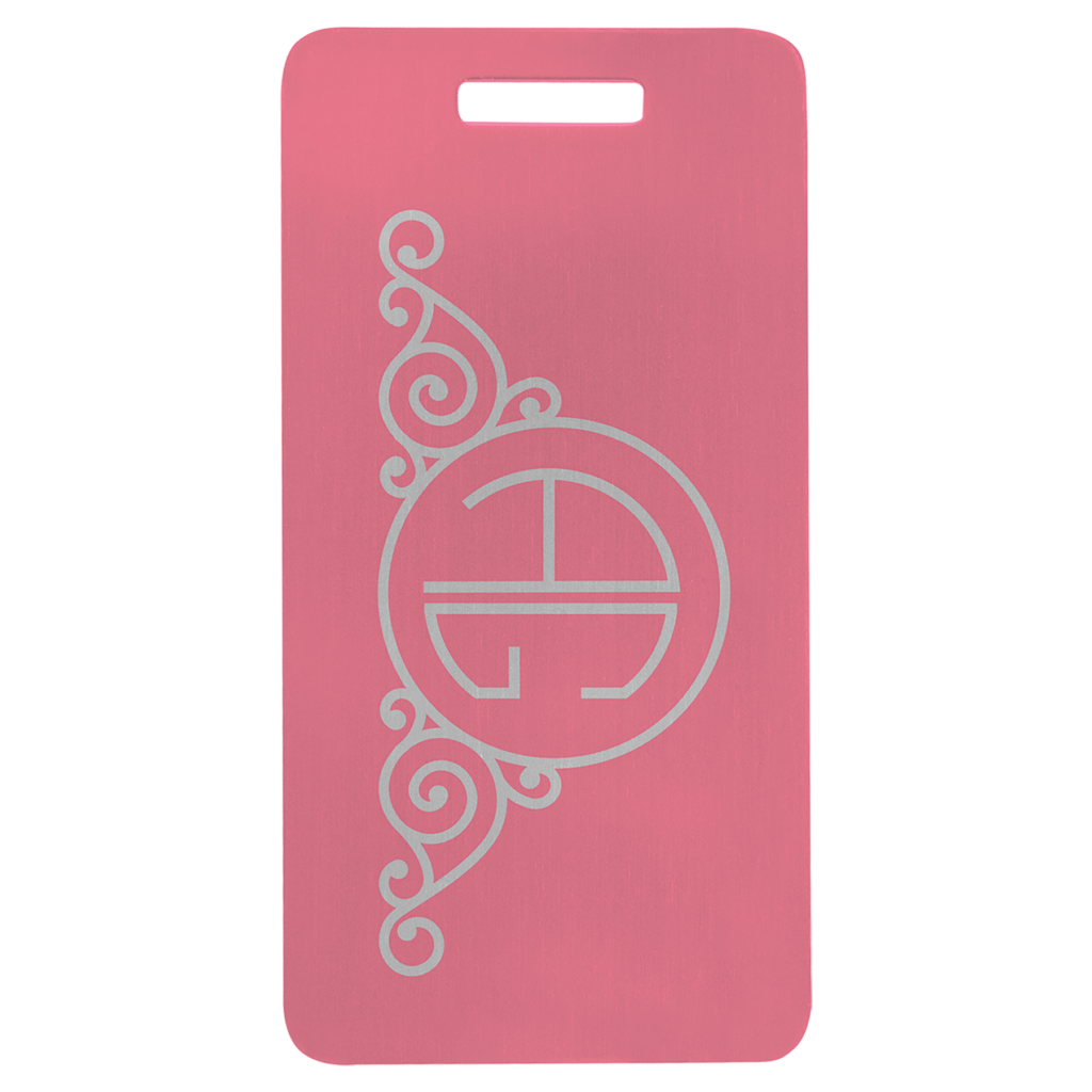 Pink anodized aluminum luggage tag with decorative swirl design and circular monogram.